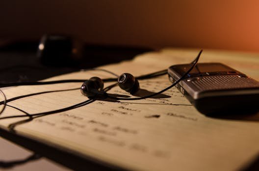 Earbuds and recorder on a notebook, perfect for studying and recording ideas. tradutor