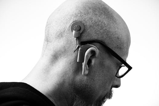 Black and white profile of a man wearing glasses and a hearing aid, studio shot. privacidade