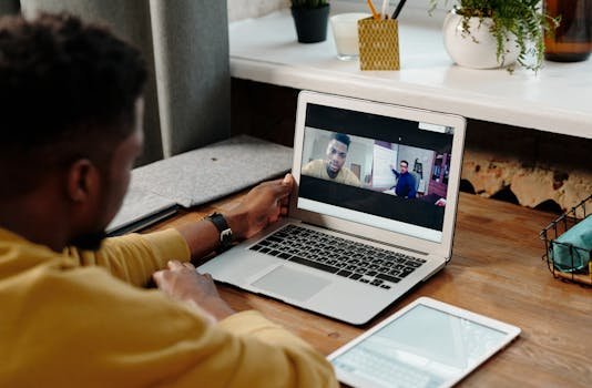 A man participates in an online video conference call from home using his laptop, fostering remote communication. remoto