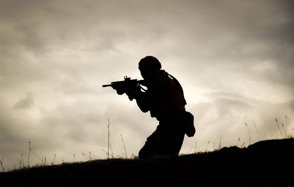 A silhouette of a soldier holding a rifle against a dramatic sunset sky.