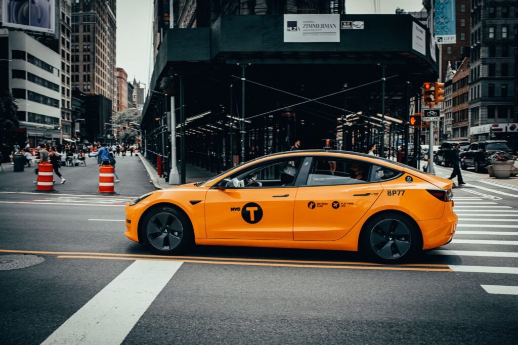 A yellow NYC taxi on a busy street in downtown New York City, showcasing urban life.